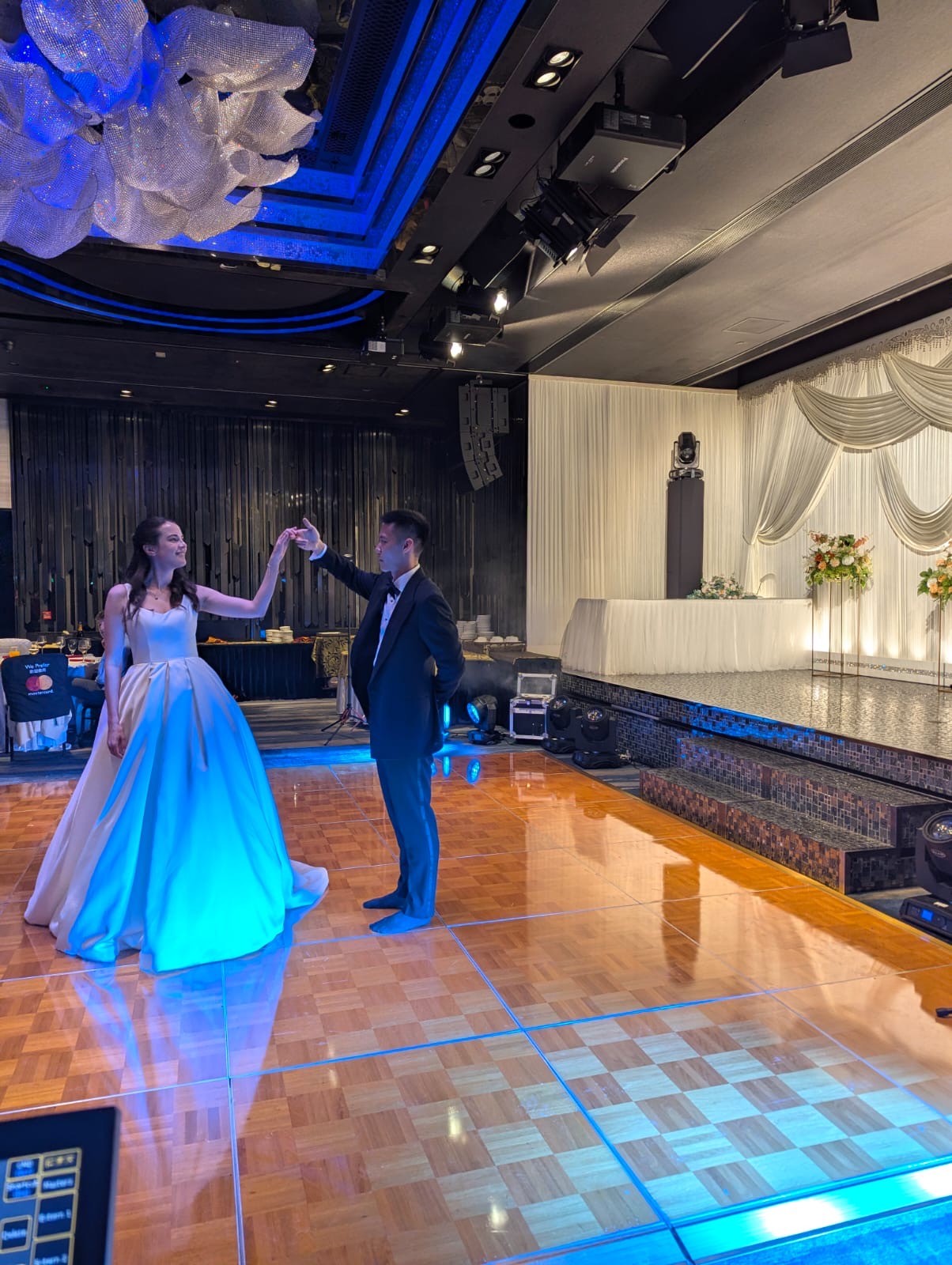 Couple dancing on a polished parquet dance floor under blue event lighting