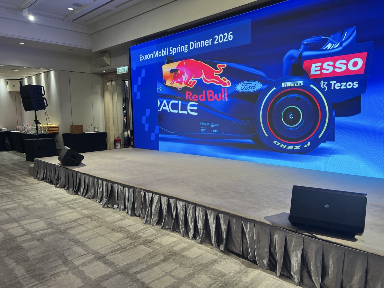Ballroom stage with a large event screen, a speaker on a stand and floor monitors