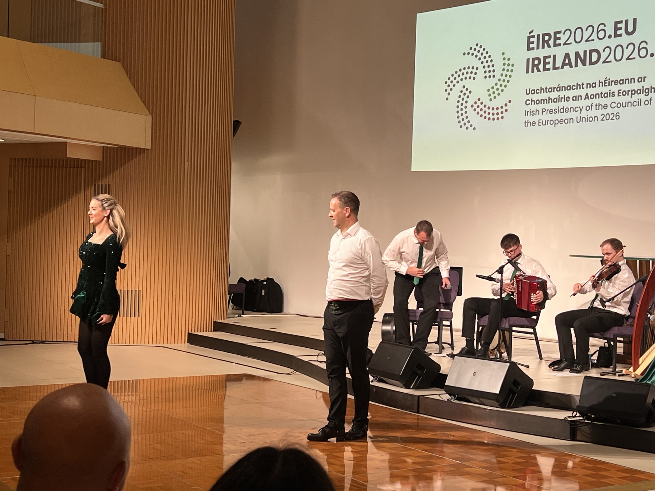 Event performers standing on a polished wooden floor with musicians on a raised stage