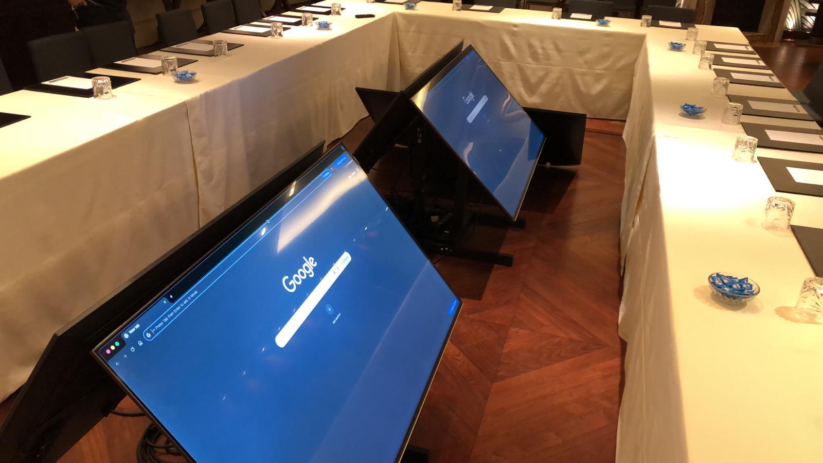 Three TVs on floor stands in a U-shaped conference room setup.