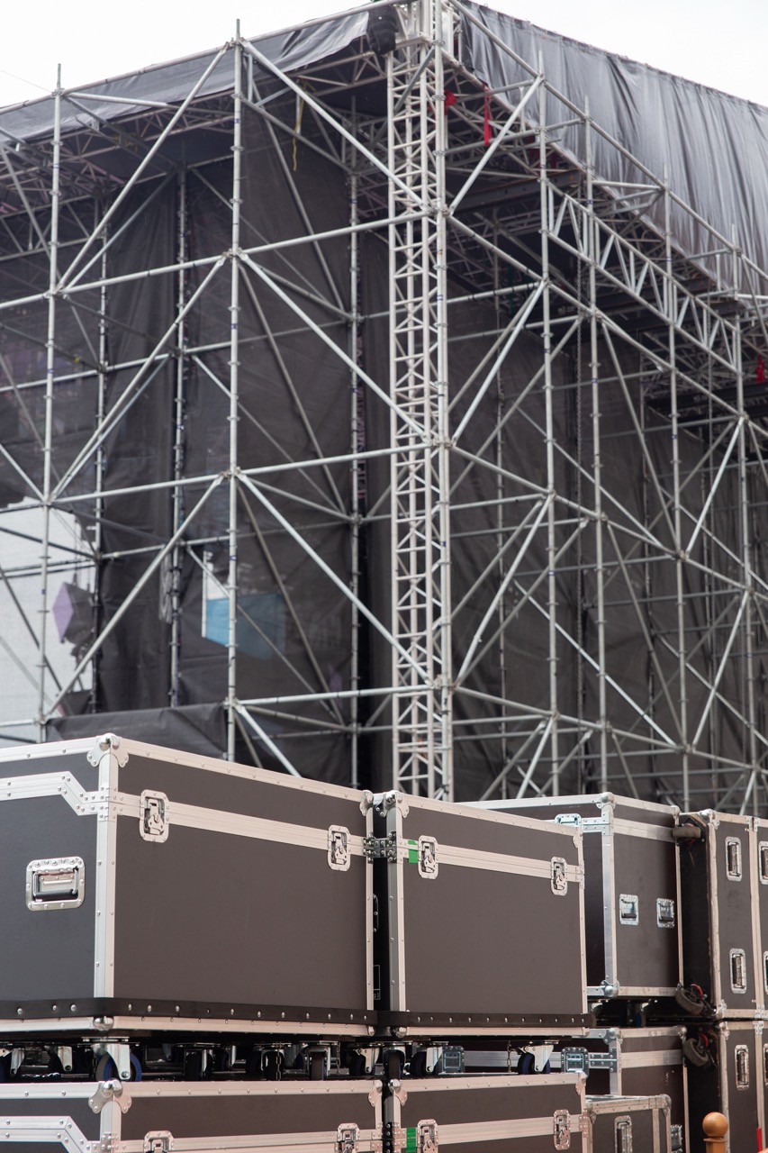 Outdoor stage scaffolding and vertical truss with stacked equipment cases in front