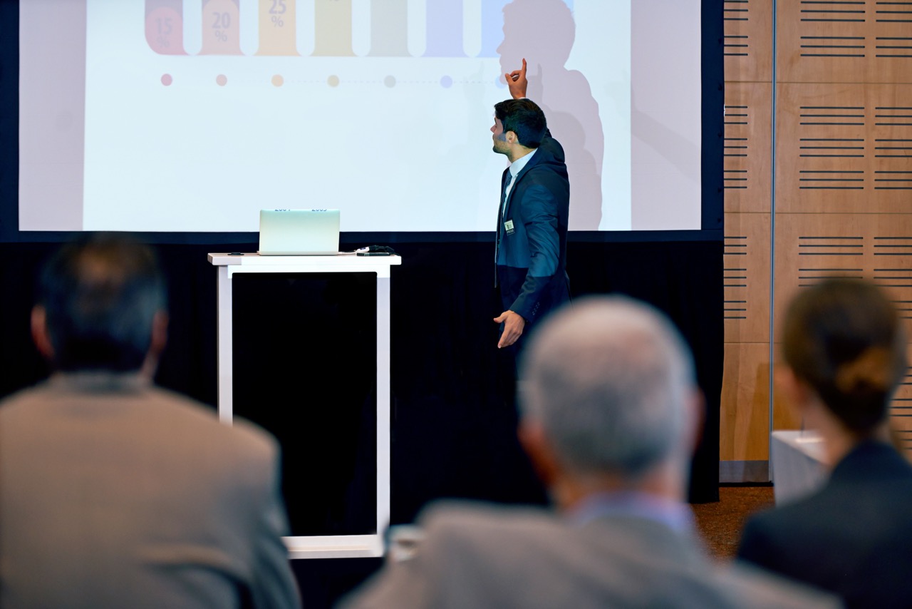 Presenter speaking beside a projector screen at a corporate seminar