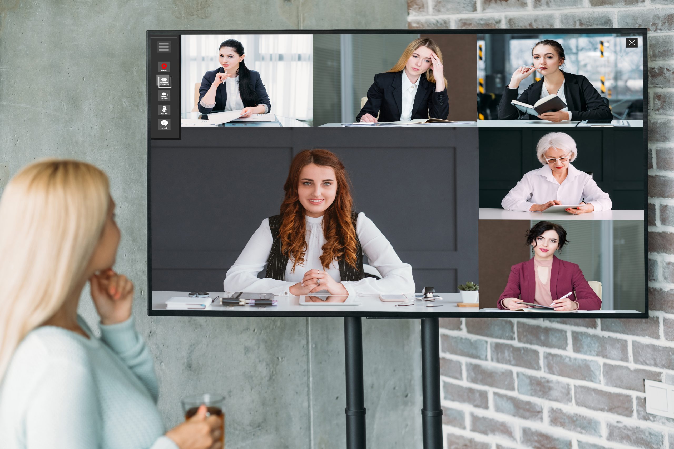 Large TV showing a video conference in a modern meeting room.