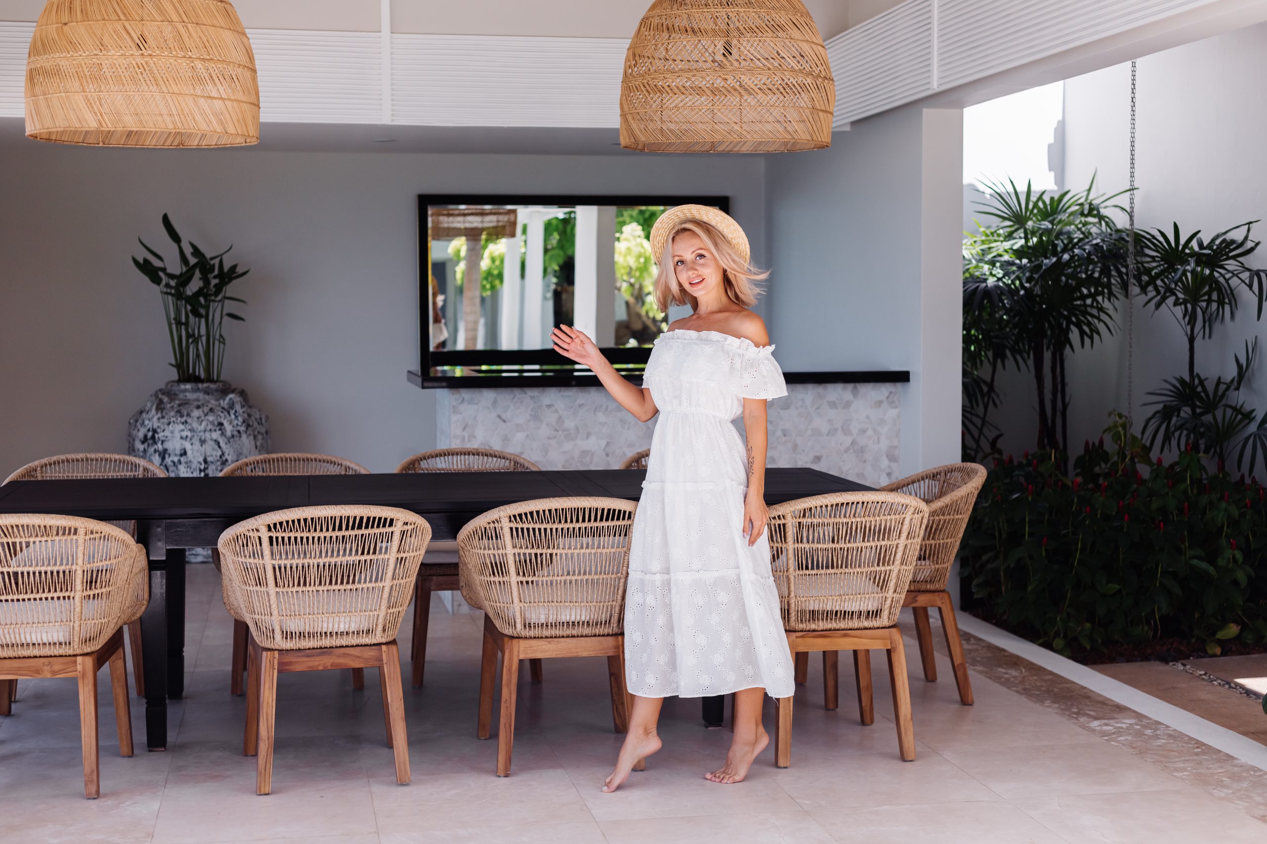 Woman beside a wall-mounted TV in a bright dining area.